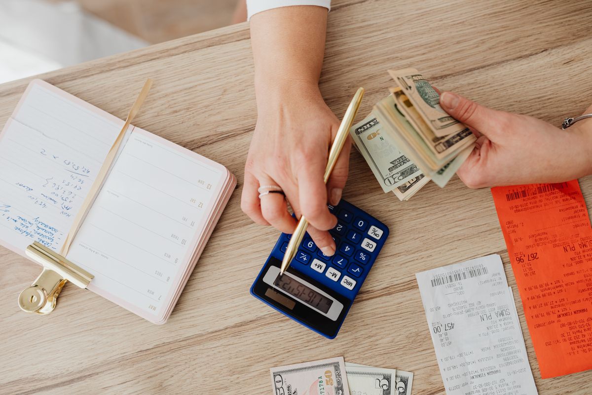 Hands reviewing receipts and cash with a calculator for a small business budget
